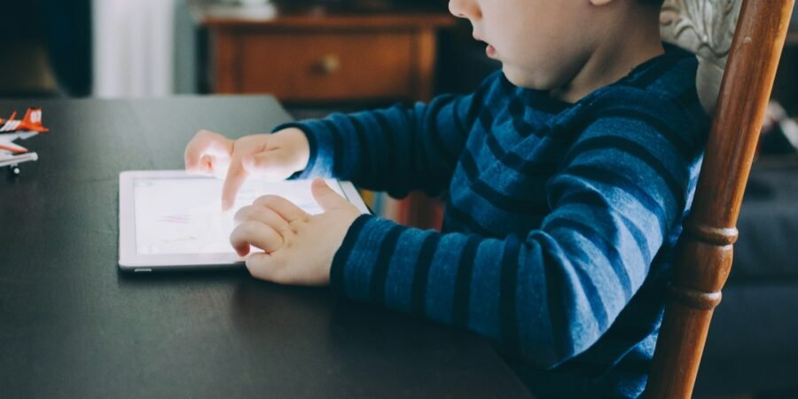 Boy sitting at a table using a tablet computer