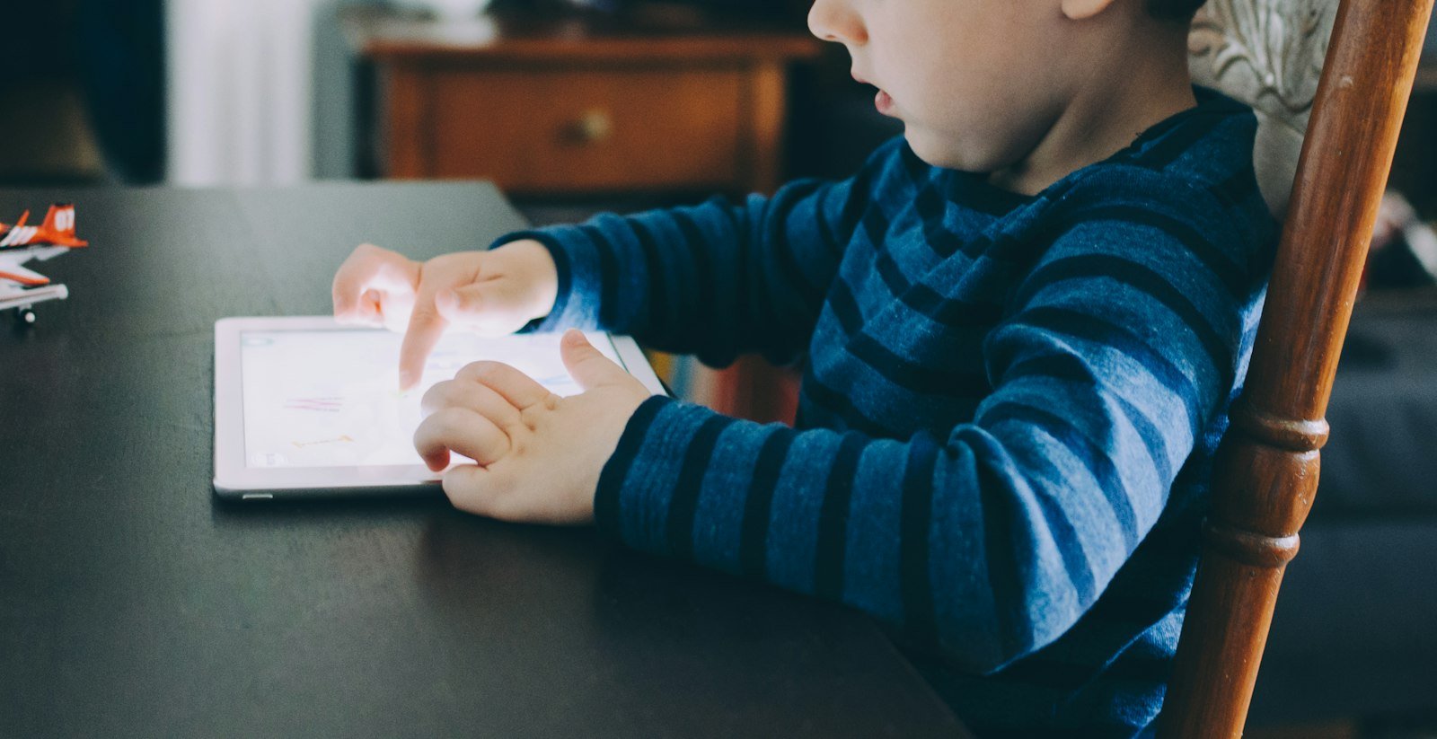 Boy sitting at a table using a tablet computer