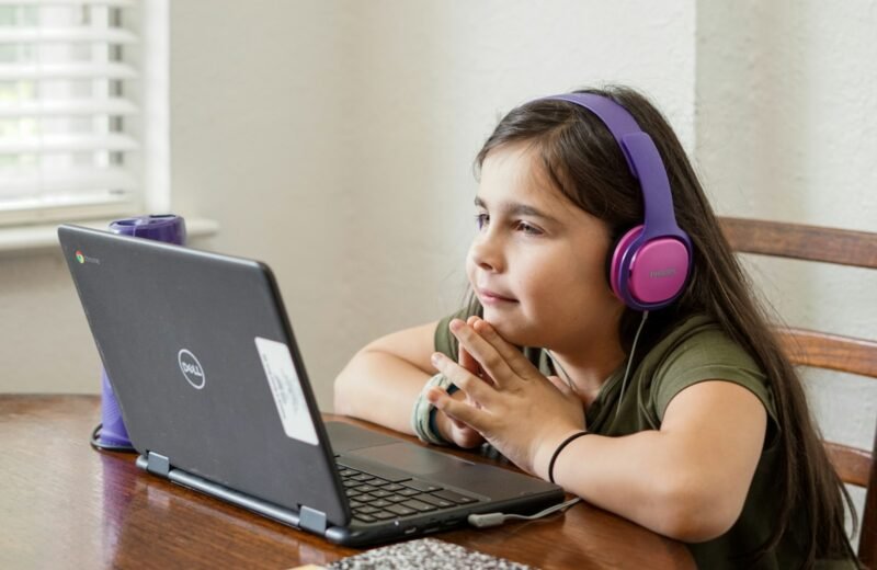 Young girl sitting at a table learning to code on a laptop