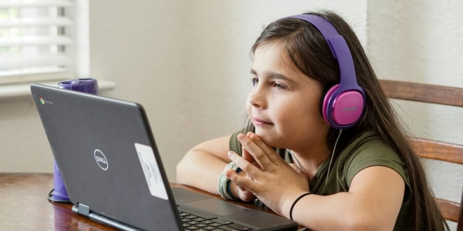Young girl sitting at a table learning to code on a laptop