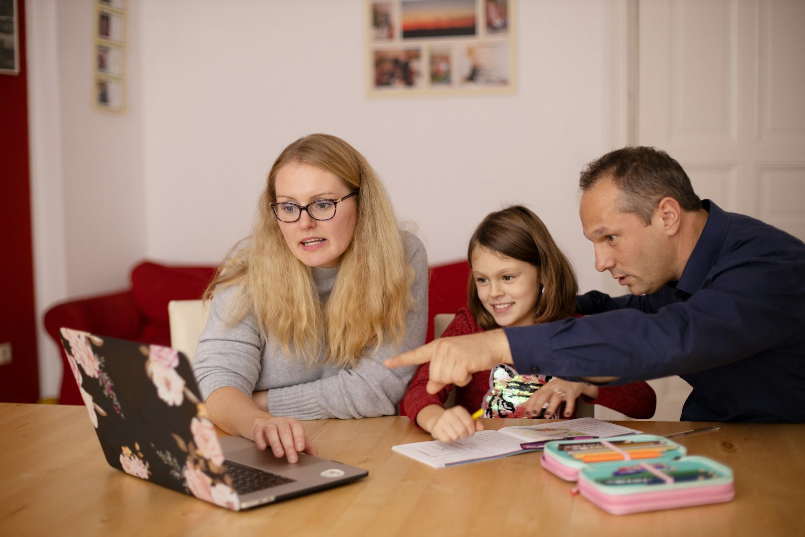 A woman and a man helping a child with schoolwork on a laptop