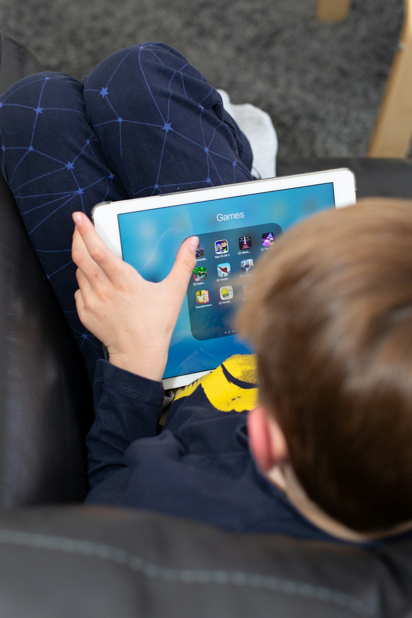 Young boy sitting on a couch holding a tablet computer