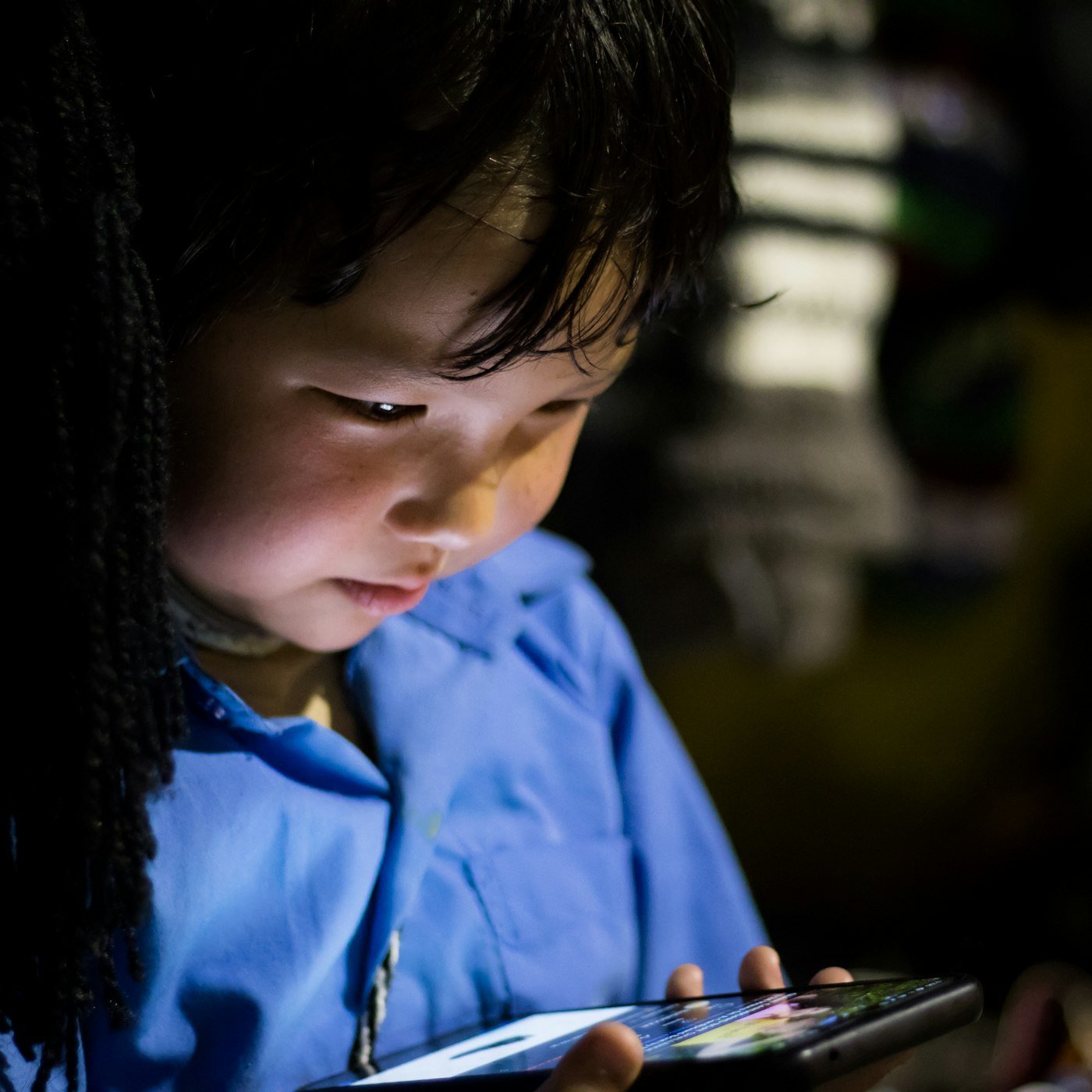A young child is looking closely at a tablet screen