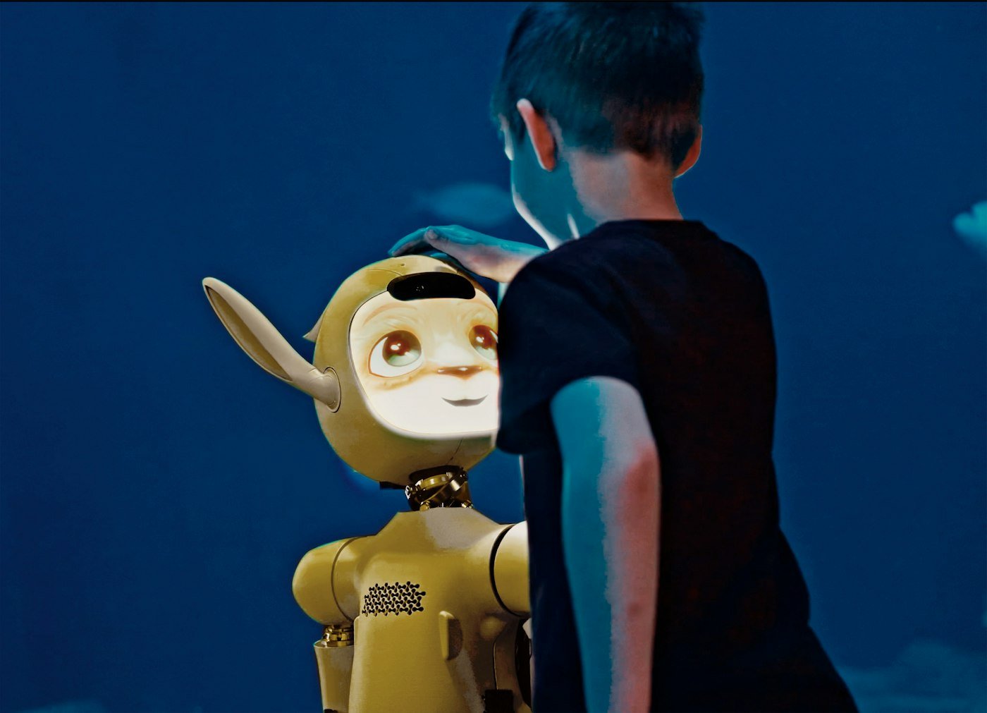 A young boy gently pats a yellow robot's head