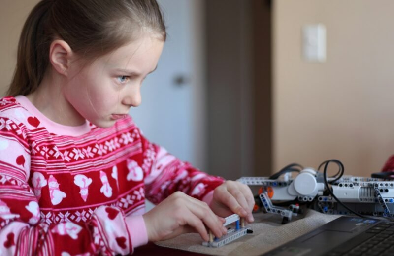 Young girl concentrating while assembling a robotics construction kit