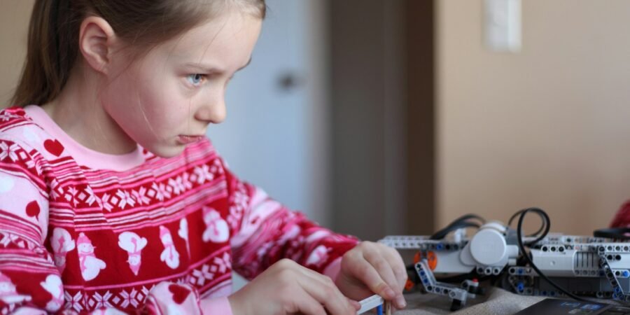 Young girl concentrating while assembling a robotics construction kit